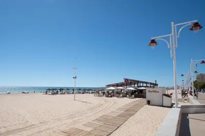 a sandy beach with a pier and the ocean at Apartamento El Rayo Verde in Cádiz