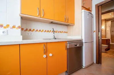 an orange kitchen with a sink and a refrigerator at Apartamento Paseo Maritimo 27 in Cádiz