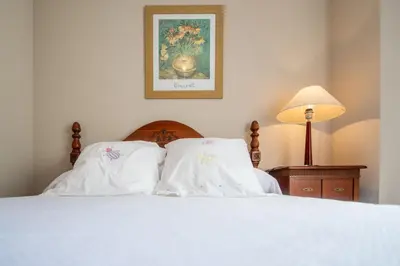a bed with white sheets and a picture on the wall at Apartamento Paseo Maritimo 27 in Cádiz