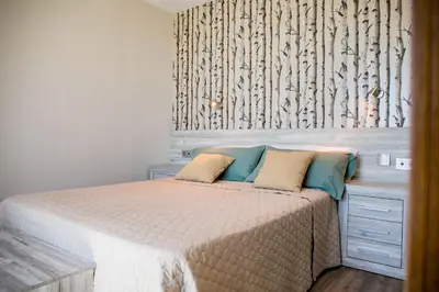 a bedroom with a bed and a wall with birch trees at Hotel Boutique Aroma de Mar in Chiclana de la Frontera