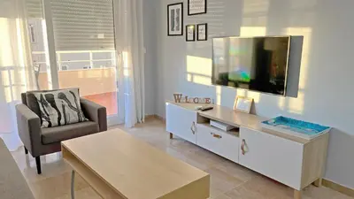a living room with a flat screen tv and a chair at Sunset Victoria Beach in Cádiz