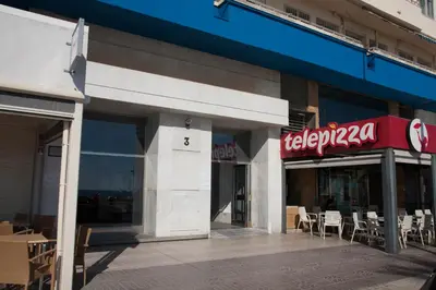 a store with a sign on the side of a building at Sunset Victoria Beach in Cádiz