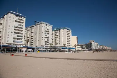 a group of buildings on a sandy beach with buildings at Sunset Victoria Beach in Cádiz