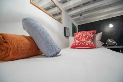 a white bed with red pillows and a gray sock on it at amazing Penthouse Cadiz in Cádiz