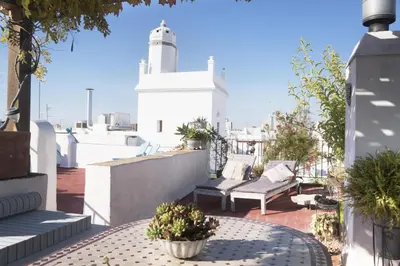 a patio with couches and a lighthouse on a roof at amazing Penthouse Cadiz in Cádiz
