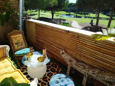 a balcony with a table and chairs and a view of a golf course at Indo en OGGOB com in Chiclana de la Frontera
