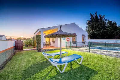 a yard with two lounge chairs and an umbrella at Chalet Miriam I in Conil de la Frontera