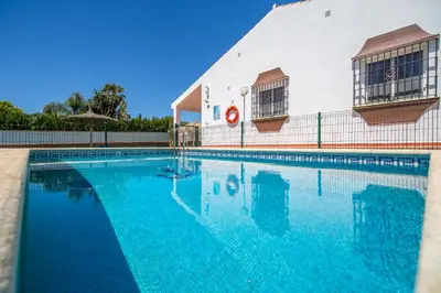 a swimming pool with blue water in front of a building at Chalet Miriam I in Conil de la Frontera