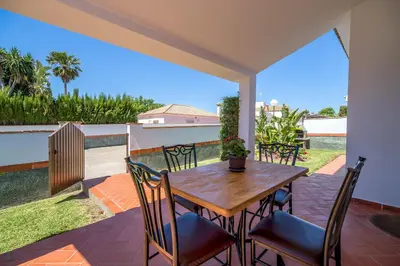 a patio with a wooden table and chairs on a balcony at Chalet Miriam I in Conil de la Frontera