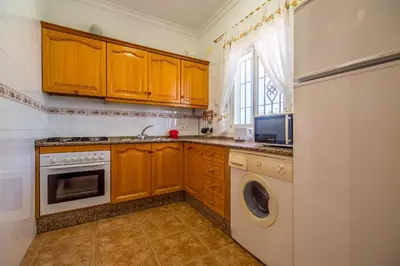 a kitchen with wooden cabinets and a washer and dryer at Chalet Miriam I in Conil de la Frontera