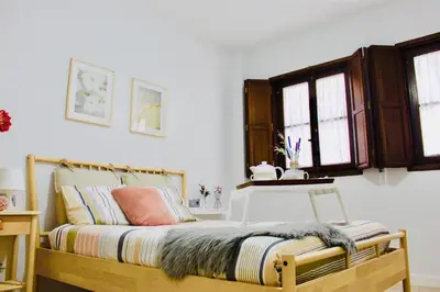 a bedroom with a bed with a wooden frame and windows at Gosol Lemon, Centro-Parking in Sanlúcar de Barrameda