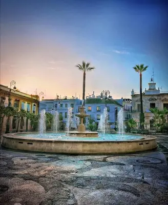 a fountain in the middle of a city with palm trees at Gosol Lemon, Centro-Parking in Sanlúcar de Barrameda