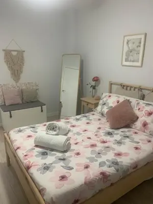 a bedroom with a bed with a floral bedspread and a mirror at Gosol Lemon, Centro-Parking in Sanlúcar de Barrameda