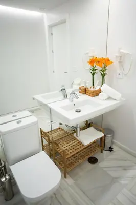 a white bathroom with a sink and a mirror at Plazuela del Carbón Suites in Cádiz