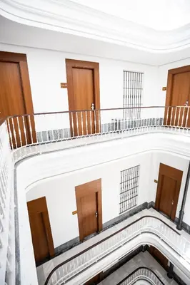 an empty building with wooden doors and a staircase at Plazuela del Carbón Suites in Cádiz