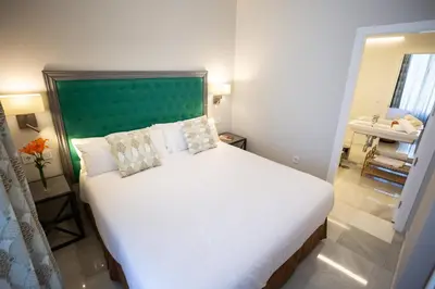 a bedroom with a large white bed with a green headboard at Plazuela del Carbón Suites in Cádiz