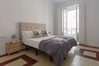 a white bedroom with a large bed and a window at SH La Casa del Loro. Amplio apartamento. in Cádiz