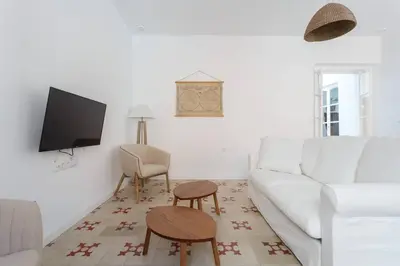 a living room with a white couch and a tv at SH La Casa del Loro. Amplio apartamento. in Cádiz