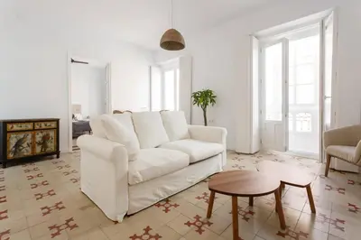 a white living room with a white couch and a table at SH La Casa del Loro. Amplio apartamento. in Cádiz