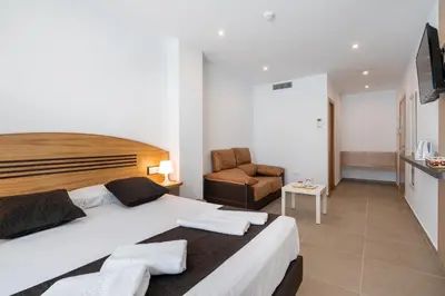 a bedroom with a large bed and a chair at Plaza de la Luz Cádiz in Cádiz