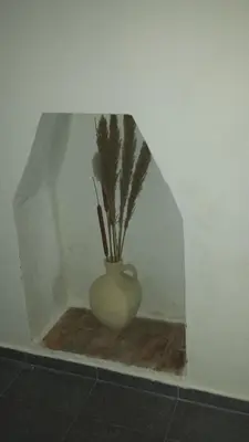 a vase with flowers in a corner of a wall at Hostal Cuesta de Belén in Arcos de la Frontera
