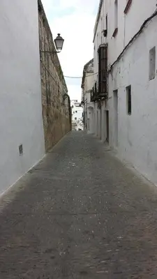 an empty alley with white buildings and a street at Hostal Cuesta de Belén in Arcos de la Frontera