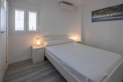 a white bedroom with a white bed and two lamps at El mirador del Mentidero in Cádiz
