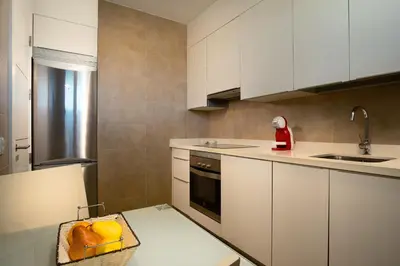 a kitchen with white cabinets and a bowl of fruit on a table at Suites Puerto Sherry in El Puerto de Santa María