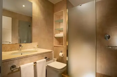 a bathroom with a sink and a toilet and a mirror at Suites Puerto Sherry in El Puerto de Santa María