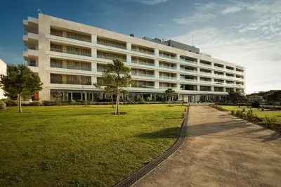 a large white building with a park in front of it at Suites Puerto Sherry in El Puerto de Santa María