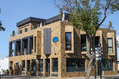a brick building with a tree in front of it at Hotel LB Lebrija by MA 22 Puntos in Lebrija
