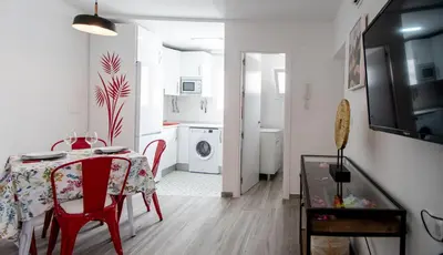 a kitchen and dining room with a table and red chairs at Apartamento Gran Sol de Cadiz in Cádiz