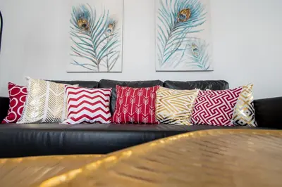 a black leather couch with colorful pillows on it at Apartamento Gran Sol de Cadiz in Cádiz