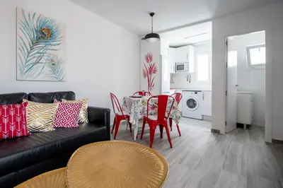 a living room with a black couch and a table and chairs at Apartamento Gran Sol de Cadiz in Cádiz