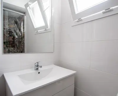 a white bathroom with a sink and a mirror at Apartamento Gran Sol de Cadiz in Cádiz