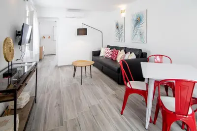 a living room with a black couch and red chairs at Apartamento Gran Sol de Cadiz in Cádiz