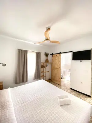 a bedroom with a white bed and a ceiling fan at Hotel Rural Casa Fina - Adults Recommended in Conil de la Frontera