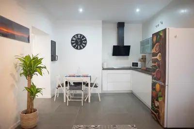 a kitchen and dining room with a table and a clock at Acogedor y luminoso apartamento in Cádiz