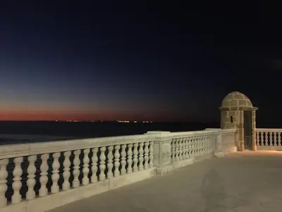 a view of the ocean from a balcony at night at Acogedor y luminoso apartamento in Cádiz