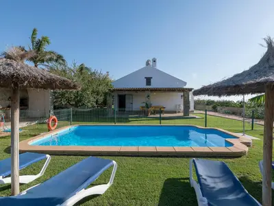 a swimming pool with two chairs and a house at Holiday Home Amado by Interhome in Conil de la Frontera