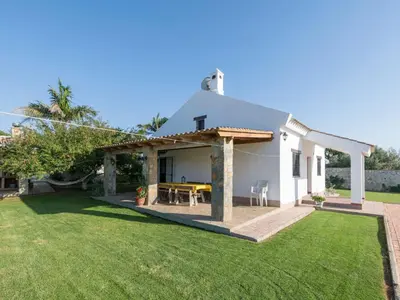 a small white house with a patio and grass at Holiday Home Amado by Interhome in Conil de la Frontera