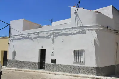 a white building with a black door on a street at Casa Alegría in Jerez de la Frontera