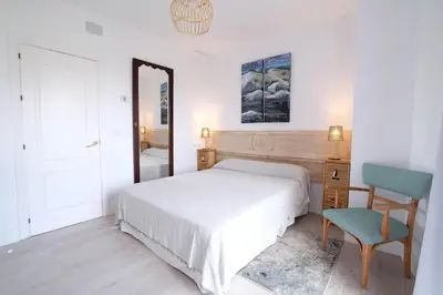 a bedroom with a bed and a chair and a mirror at Fabuloso Ático con vistas al mar in Cádiz