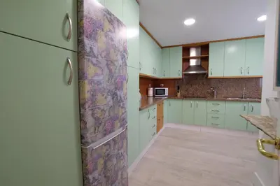 a kitchen with green cabinets and a colorful wall at Fabuloso Ático con vistas al mar in Cádiz