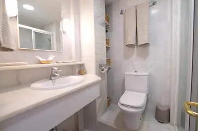 a white bathroom with a toilet and a sink at Fabuloso Ático con vistas al mar in Cádiz