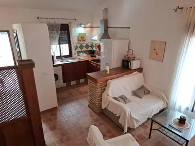 a kitchen with a table and a couch in a room at Cortijo El Almendro, Urb. Fuente del Gallo, Conil in Conil de la Frontera