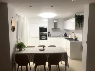a white kitchen with a table and chairs in it at Masai Victoria Beach. A 100 metros de la playa. in Cádiz