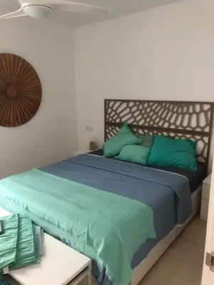 a bedroom with a large bed with green pillows at Masai Victoria Beach. A 100 metros de la playa. in Cádiz