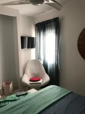 a white chair with a red seat in a bedroom at Masai Victoria Beach. A 100 metros de la playa. in Cádiz