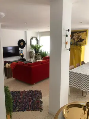 a living room with a red couch and a bed at Masai Victoria Beach. A 100 metros de la playa. in Cádiz
